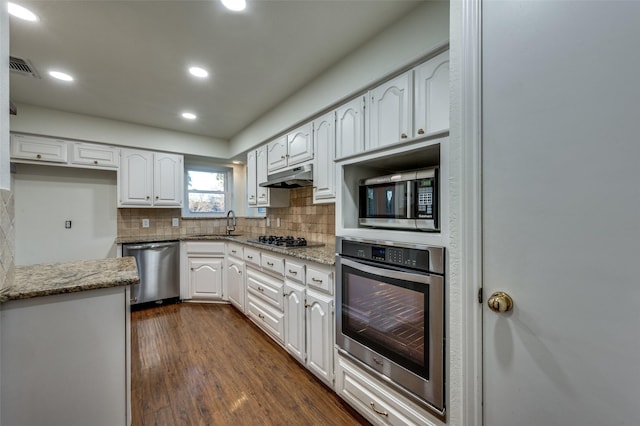 kitchen featuring backsplash, stainless steel appliances, light stone countertops, and white cabinets