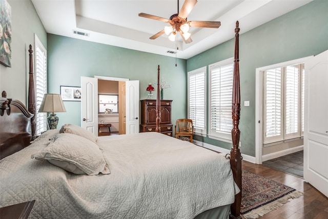 bedroom with dark wood-type flooring, a raised ceiling, and ceiling fan