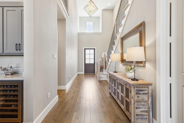 foyer entrance with a high ceiling, dark hardwood / wood-style flooring, and beverage cooler