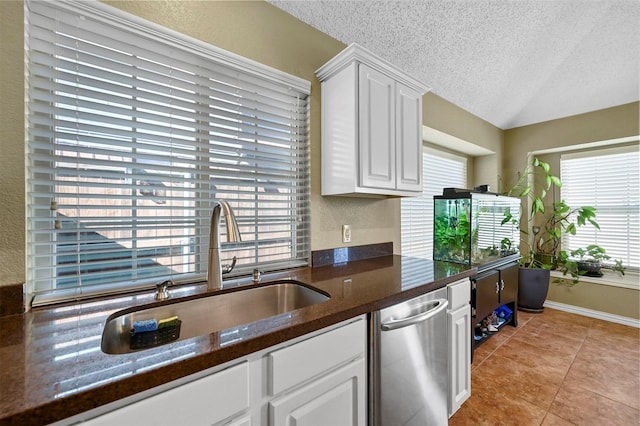 kitchen featuring light tile patterned floors, a textured ceiling, sink, white cabinetry, and stainless steel dishwasher