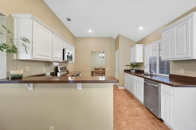 kitchen with appliances with stainless steel finishes, kitchen peninsula, white cabinets, and sink