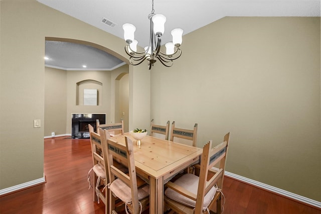 dining room featuring lofted ceiling, dark hardwood / wood-style flooring, ornamental molding, and a notable chandelier