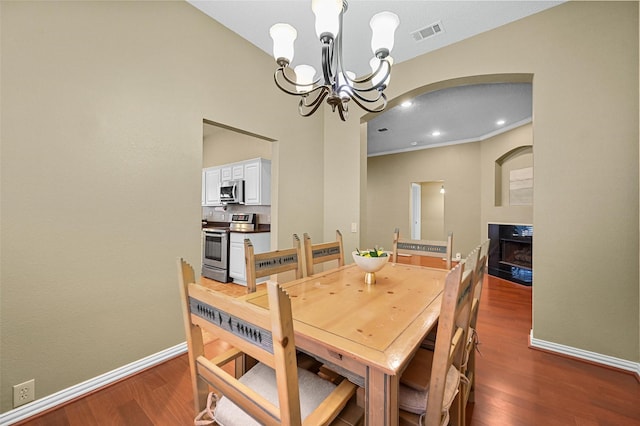 dining area featuring dark wood-type flooring, a multi sided fireplace, and a chandelier