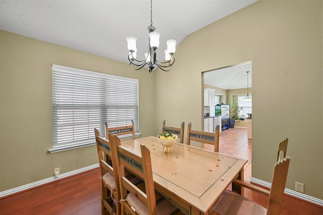 dining area featuring vaulted ceiling, a chandelier, and wood-type flooring