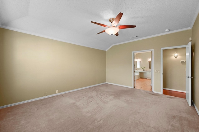 unfurnished bedroom with ensuite bath, a textured ceiling, light colored carpet, crown molding, and ceiling fan