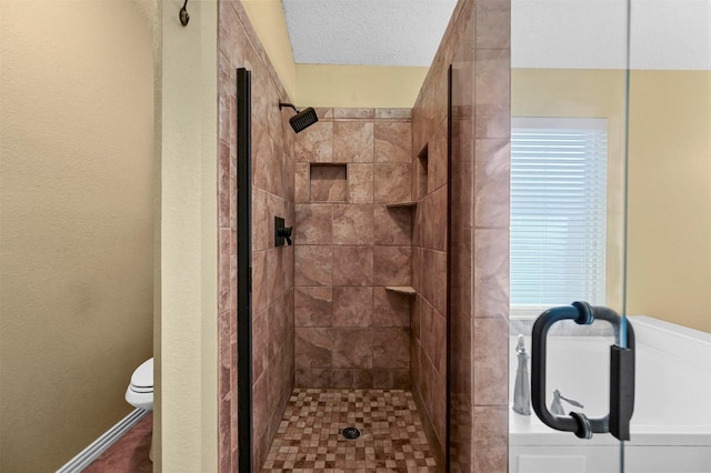 bathroom featuring toilet, a shower with door, and a textured ceiling