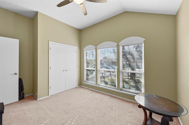 living area featuring a textured ceiling, ceiling fan, vaulted ceiling, and light carpet