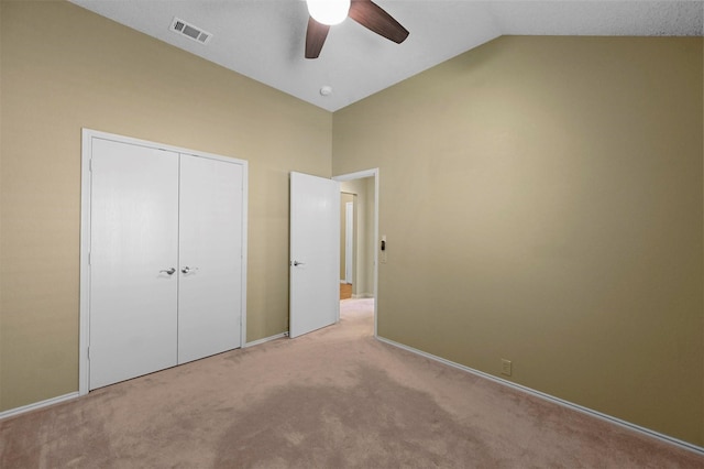 unfurnished bedroom featuring lofted ceiling, a closet, ceiling fan, and light colored carpet