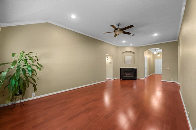 unfurnished living room with vaulted ceiling, a tiled fireplace, ornamental molding, ceiling fan, and hardwood / wood-style flooring