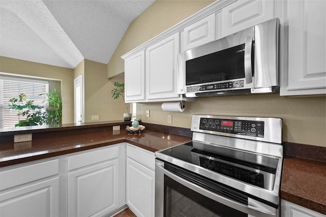 kitchen with stainless steel appliances, vaulted ceiling, white cabinetry, and a textured ceiling