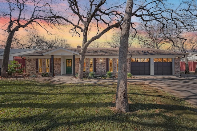 ranch-style house with a garage and a yard