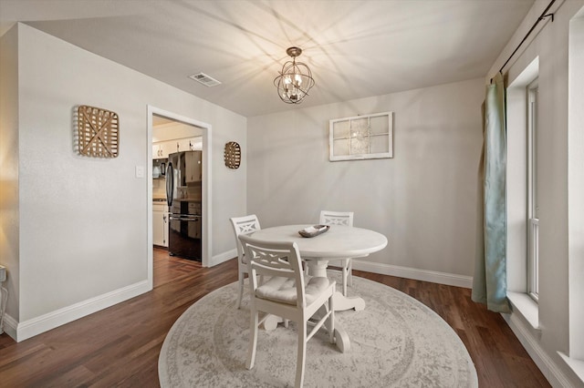 dining space featuring dark wood-type flooring and a chandelier