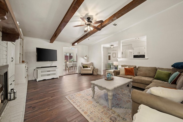 living room featuring a brick fireplace, dark wood-type flooring, lofted ceiling with beams, and ceiling fan