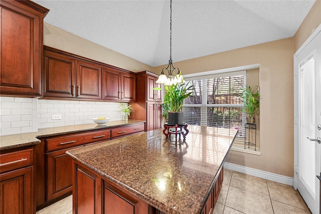 kitchen with a kitchen island, dark stone countertops, vaulted ceiling, and light tile patterned floors