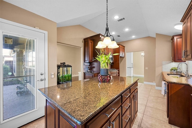 kitchen with a center island, dark stone countertops, hanging light fixtures, and sink