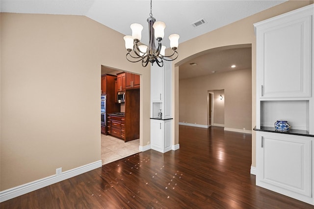 unfurnished dining area with light hardwood / wood-style flooring, an inviting chandelier, vaulted ceiling, and built in features