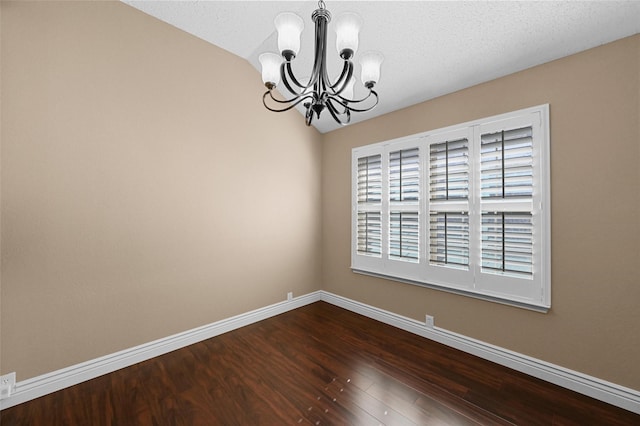 spare room with a textured ceiling, a chandelier, and dark hardwood / wood-style floors