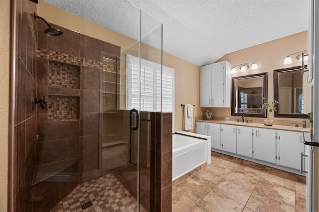 bathroom with vanity, a textured ceiling, vaulted ceiling, and separate shower and tub