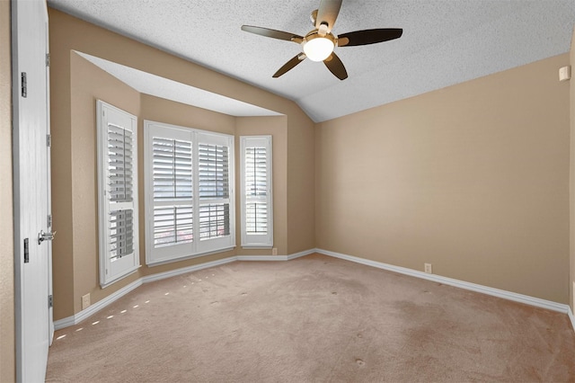 unfurnished room with lofted ceiling, a textured ceiling, ceiling fan, and light colored carpet