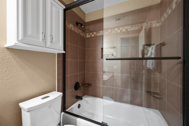 bathroom featuring a textured ceiling, toilet, and combined bath / shower with glass door