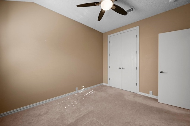 unfurnished bedroom featuring a textured ceiling, lofted ceiling, light carpet, ceiling fan, and a closet