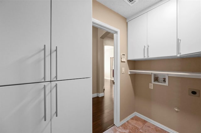 clothes washing area with washer hookup, cabinets, and hookup for an electric dryer