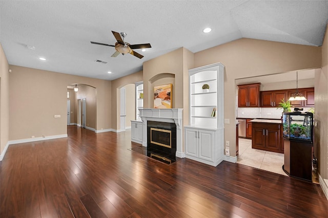 unfurnished living room with ceiling fan, hardwood / wood-style floors, lofted ceiling, and a textured ceiling