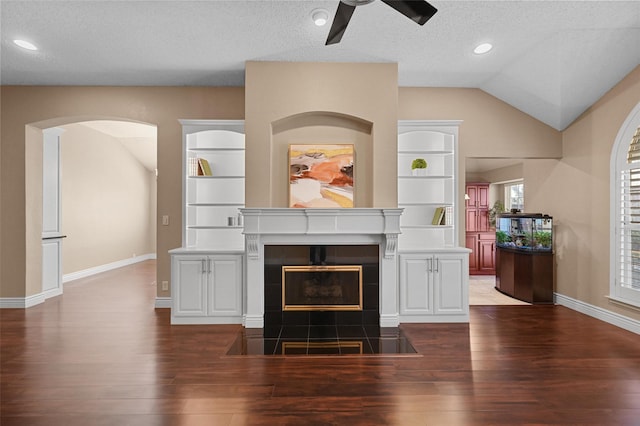 unfurnished living room with a tiled fireplace, a textured ceiling, and built in features