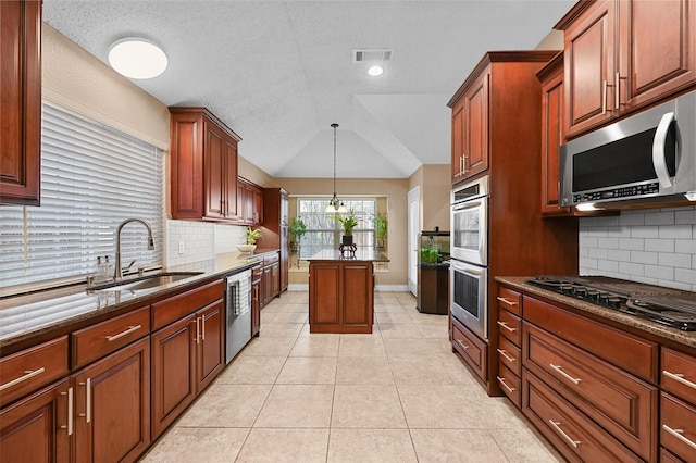 kitchen with vaulted ceiling, stainless steel appliances, pendant lighting, sink, and tasteful backsplash