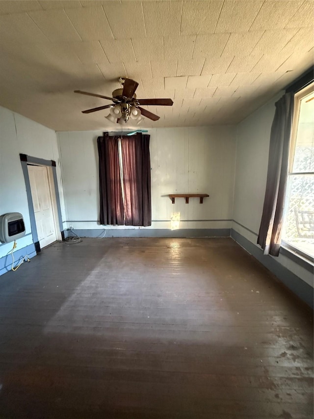 spare room featuring ceiling fan, heating unit, and dark hardwood / wood-style floors