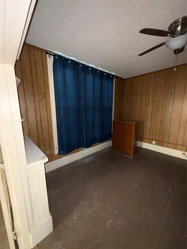 spare room featuring ceiling fan and wood walls