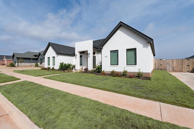 view of front of property with brick siding, a front yard, and fence