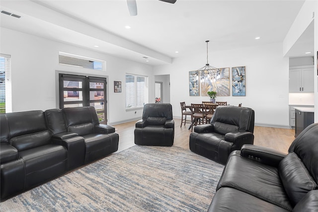 living room with ceiling fan with notable chandelier and light hardwood / wood-style flooring