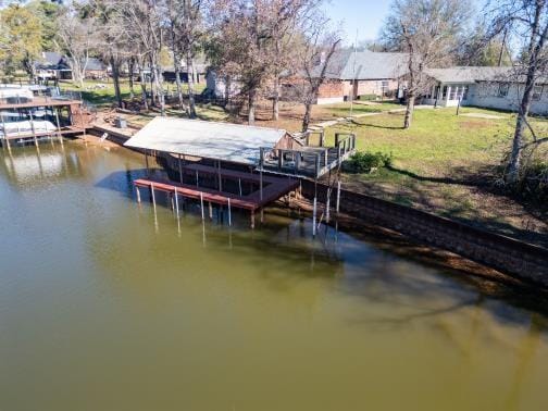 view of dock with a yard and a water view