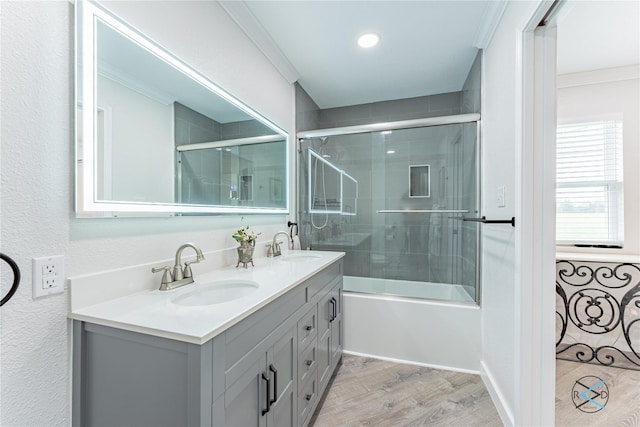 bathroom with wood-type flooring, vanity, combined bath / shower with glass door, and ornamental molding