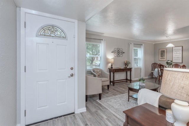 entrance foyer featuring light hardwood / wood-style floors, ornamental molding, and a textured ceiling