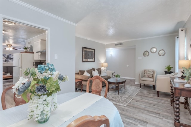 dining space with ornamental molding, ceiling fan, and light hardwood / wood-style floors