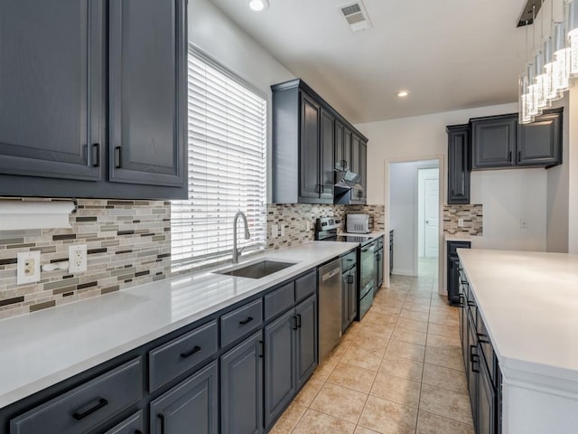 kitchen featuring stainless steel appliances, sink, decorative light fixtures, light tile patterned floors, and a healthy amount of sunlight