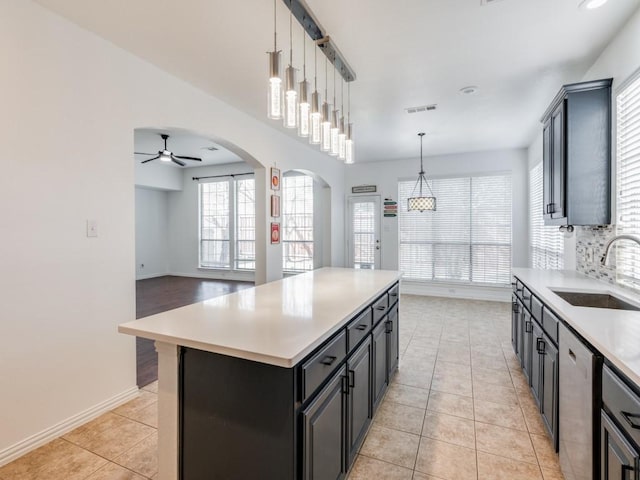 kitchen with stainless steel dishwasher, pendant lighting, a kitchen island, ceiling fan, and sink