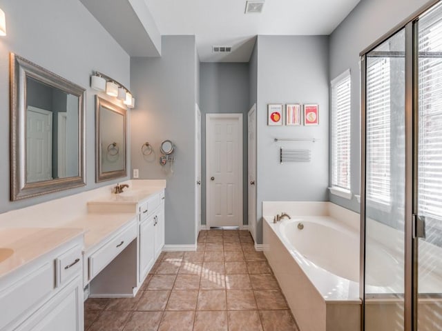 bathroom featuring vanity, tile patterned floors, a relaxing tiled tub, and plenty of natural light