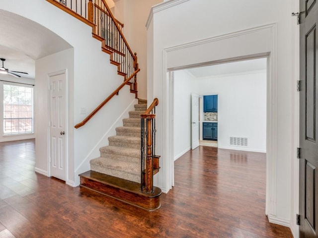 staircase with ornamental molding, ceiling fan, and hardwood / wood-style floors