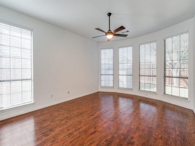 empty room with ceiling fan, dark wood-type flooring, and a wealth of natural light