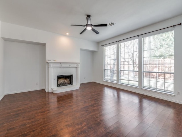 unfurnished living room with ceiling fan, a brick fireplace, and dark hardwood / wood-style floors