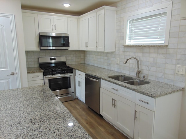 kitchen with white cabinets, appliances with stainless steel finishes, tasteful backsplash, and sink