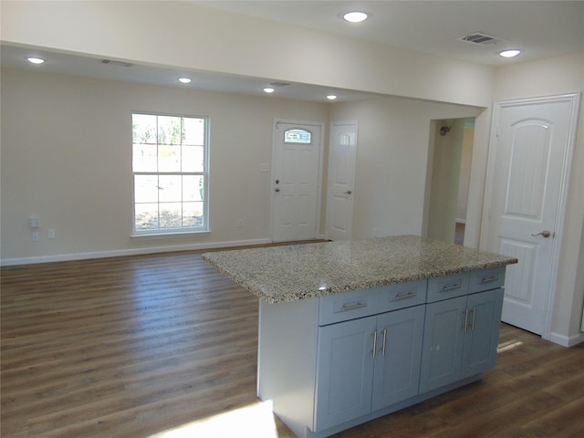 kitchen with light stone countertops, dark wood-type flooring, and a kitchen island