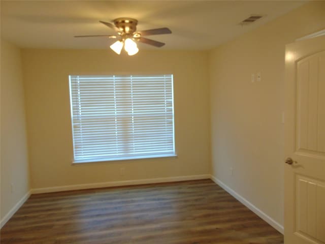 empty room with ceiling fan and dark hardwood / wood-style flooring