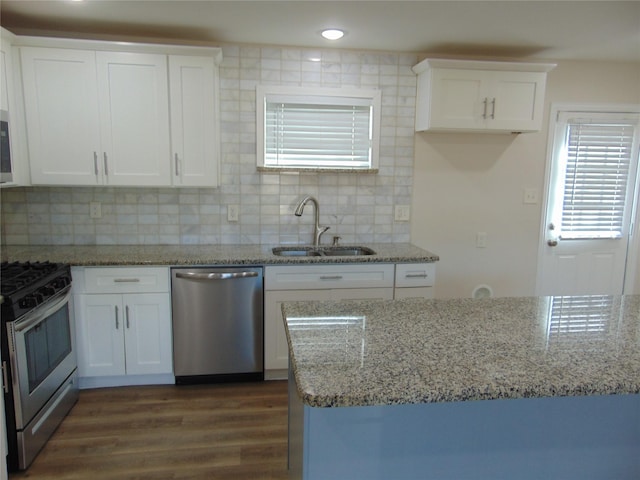 kitchen with light stone counters, stainless steel appliances, tasteful backsplash, white cabinetry, and sink