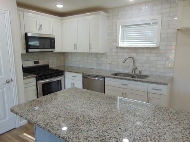 kitchen with light stone counters, stainless steel appliances, backsplash, and white cabinetry