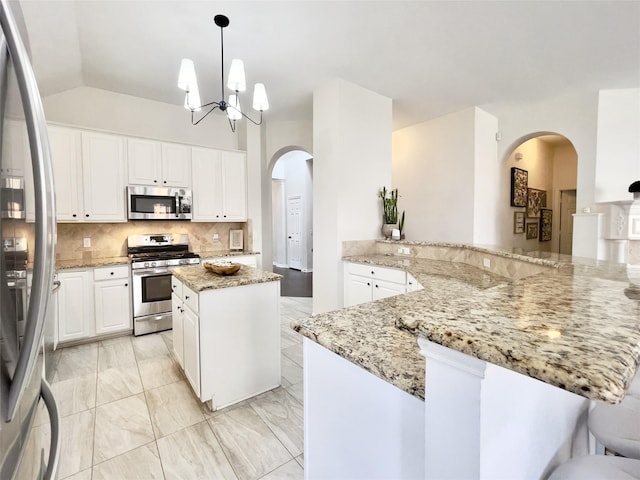 kitchen with kitchen peninsula, light stone countertops, pendant lighting, stainless steel appliances, and white cabinetry