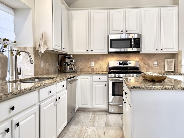 kitchen with stainless steel appliances, stone countertops, white cabinets, and sink